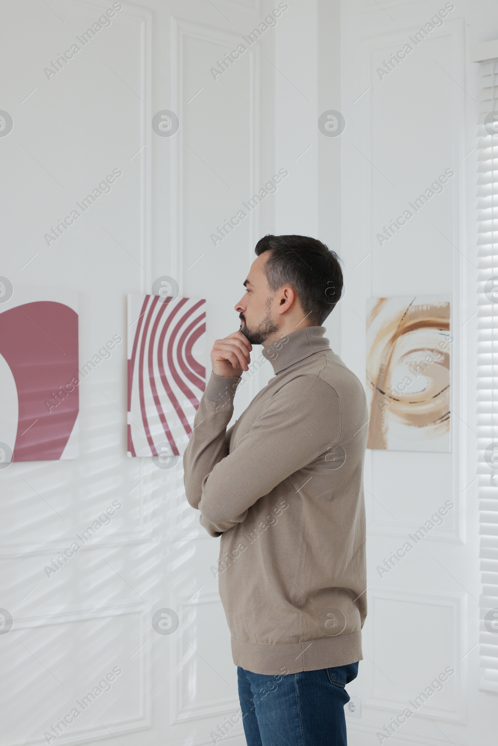 Photo of Man studying beautiful artwork in modern gallery