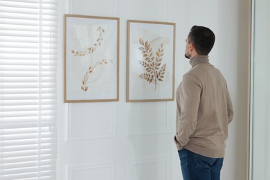 Photo of Man studying beautiful artwork in modern gallery