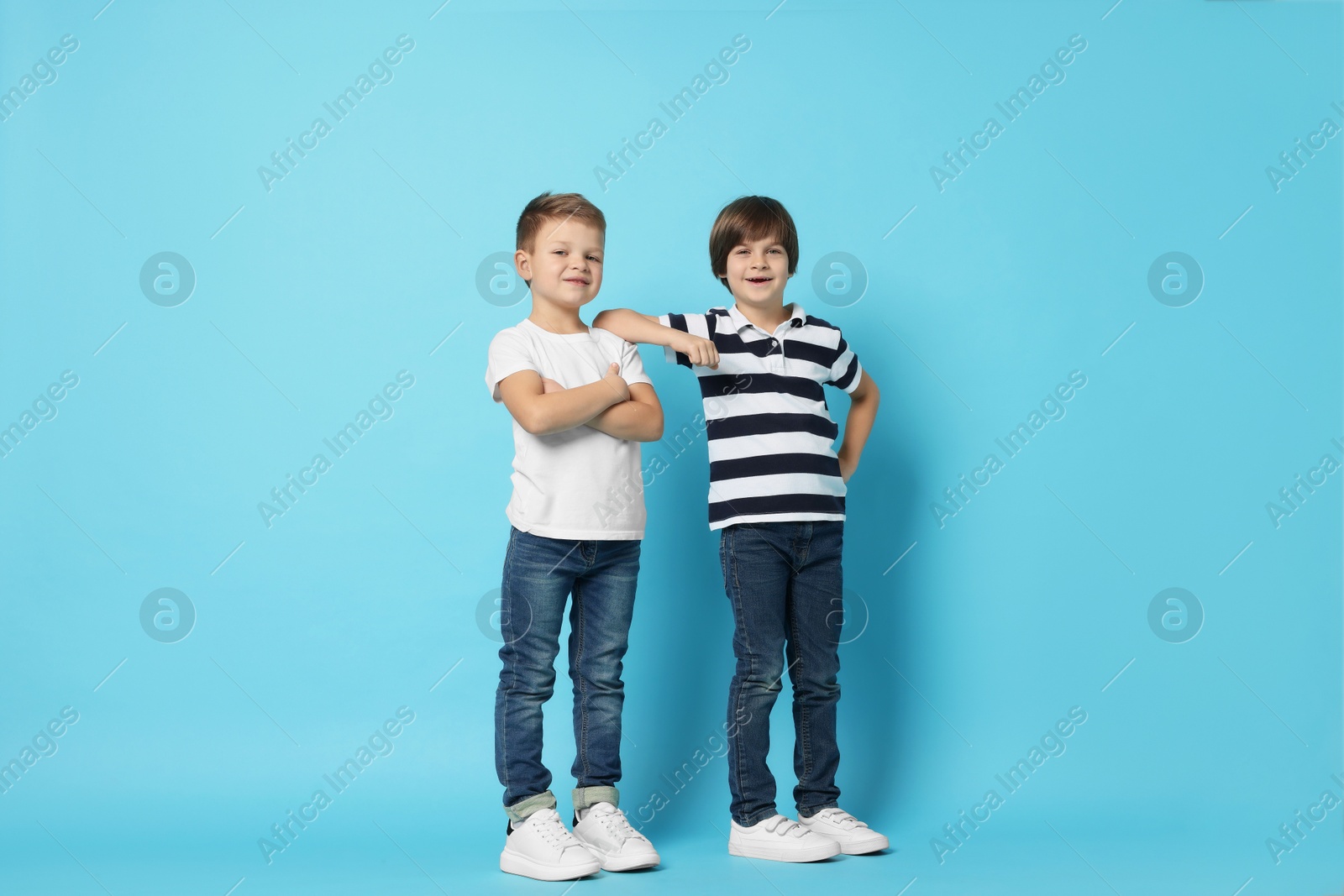 Photo of Cute brothers posing on light blue background