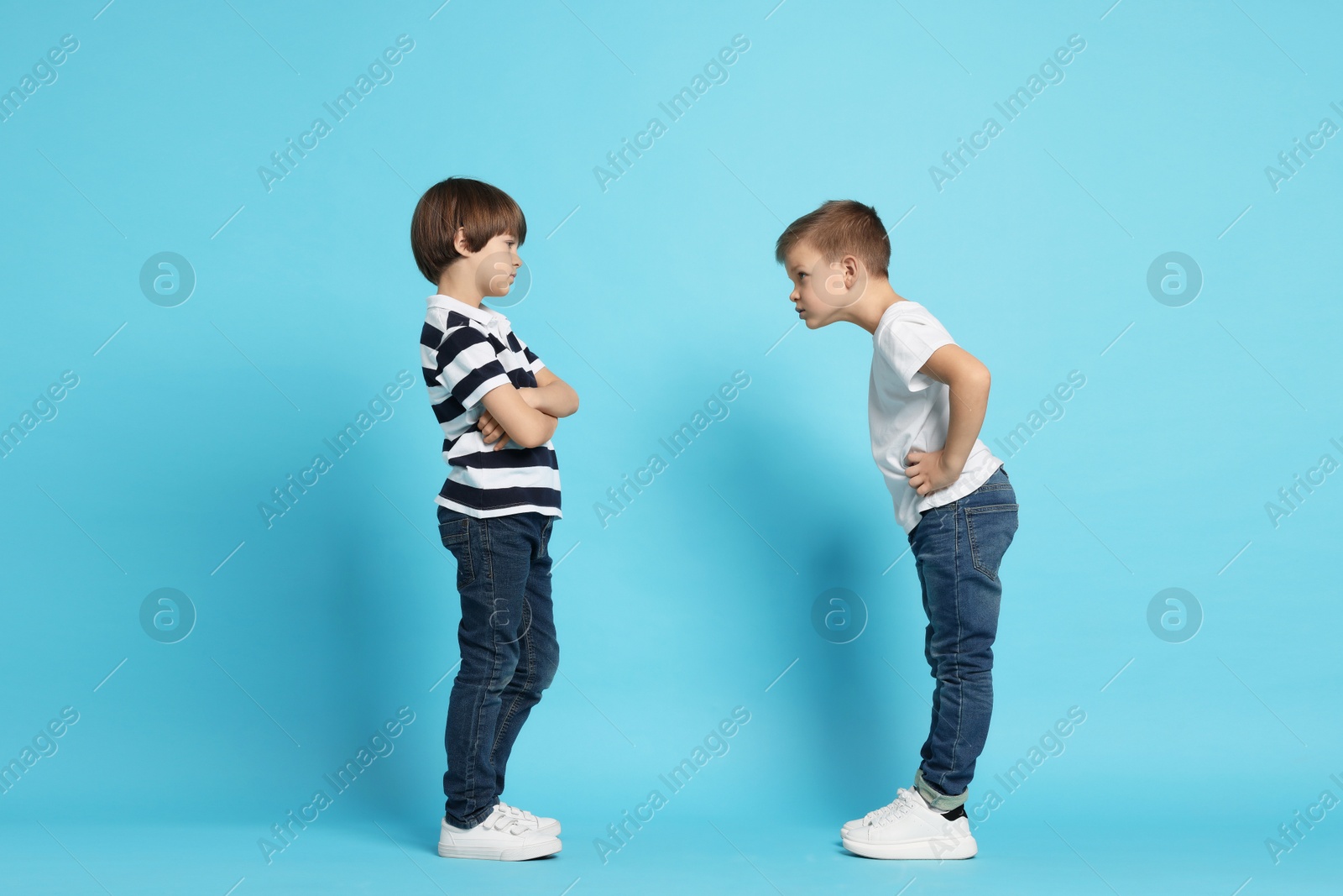 Photo of Angry brothers arguing on light blue background