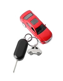 Photo of Car key with keychain and toy isolated on white, top view. Buying auto