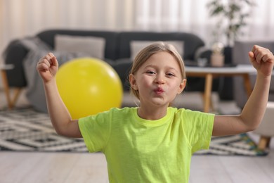 Cute little girl showing her biceps indoors