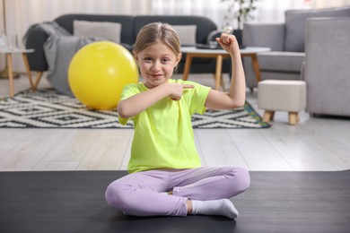 Photo of Cute little girl showing her bicep indoors