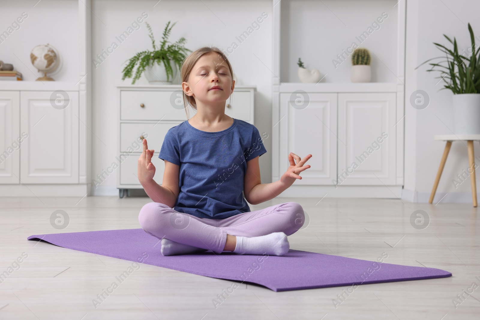 Photo of Cute little girl exercising on fitness mat indoors