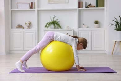 Cute little girl with fitness ball indoors