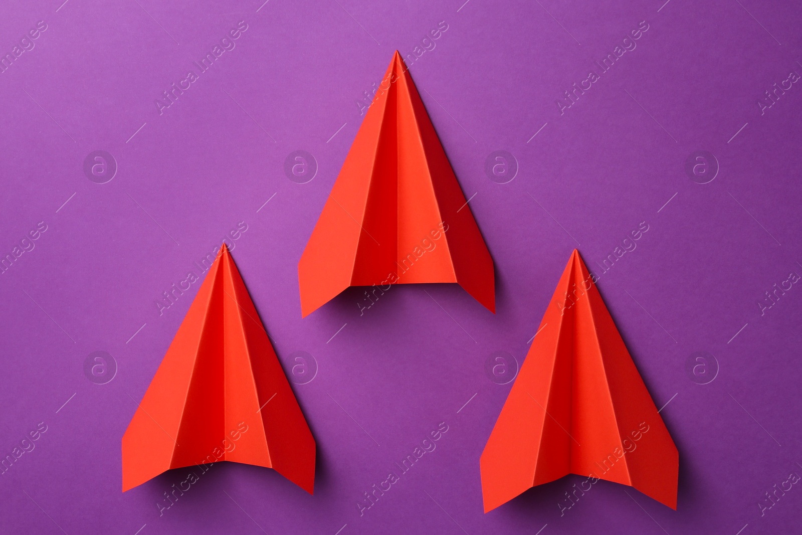 Photo of Red paper planes on purple background, top view