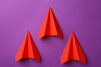 Photo of Red paper planes on purple background, top view