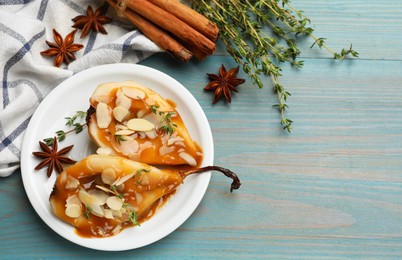 Photo of Delicious pears with caramel sauce, almond flakes and spices on blue wooden table, flat lay