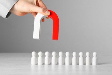 Photo of Woman with magnet attracting wooden human figures at light table, closeup