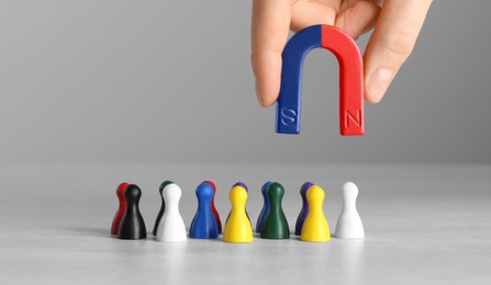 Photo of Woman with magnet attracting colorful game pieces at light table, closeup