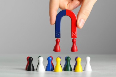 Photo of Woman with magnet attracting colorful game pieces at light table, closeup