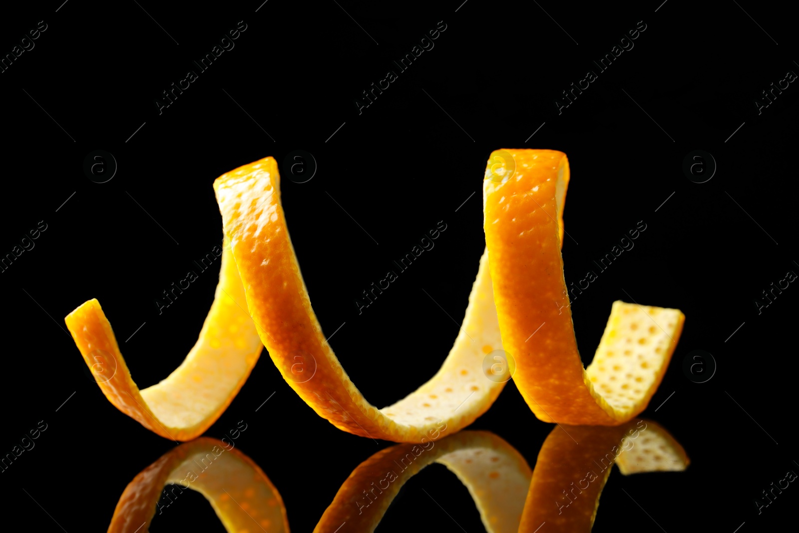 Photo of One fresh orange peel on black mirror surface, closeup