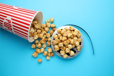 Photo of Sweet popcorn and film reel on light blue background, top view. Watching movie