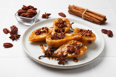 Photo of Delicious pears with caramel sauce, pecan nuts and spices on white table, closeup