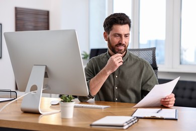 Photo of Man with document working at table in office