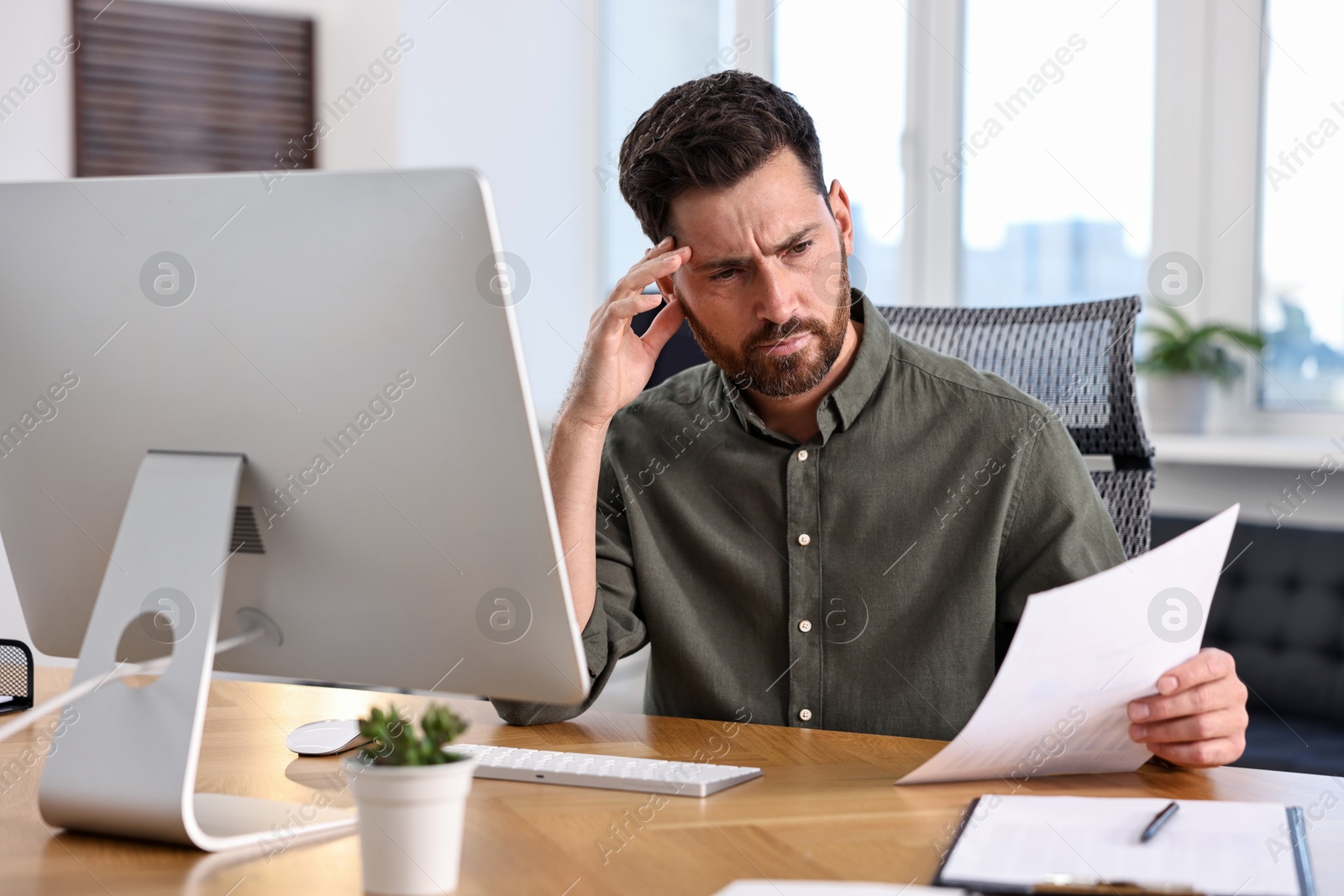 Photo of Man with document working at table in office