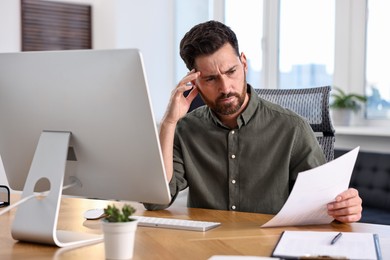 Photo of Man with document working at table in office