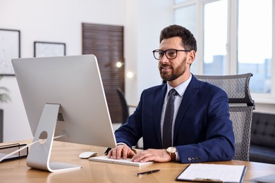 Photo of Man working on computer at table in office