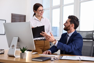 Photo of Colleagues working with computer at desk in office