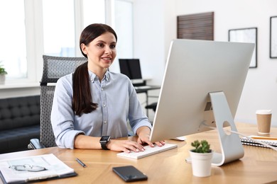 Photo of Woman working on computer at table in office