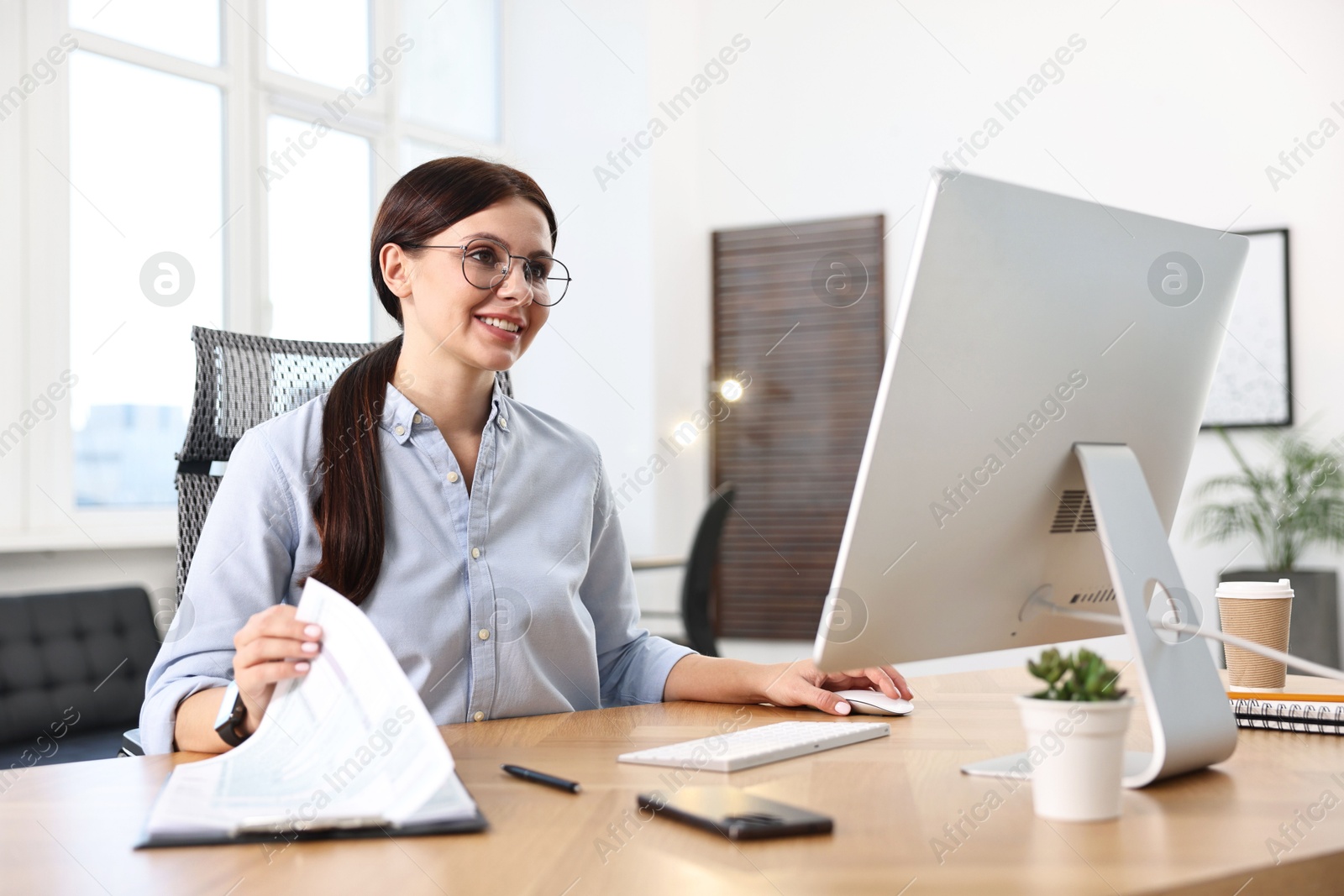 Photo of Woman working on computer at table in office