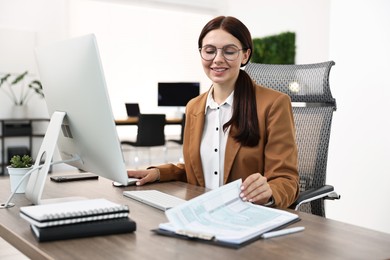 Photo of Woman working on computer at table in office