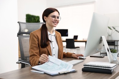 Photo of Woman working on computer at table in office