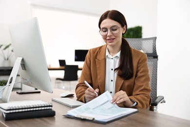 Photo of Woman working with document at table in office