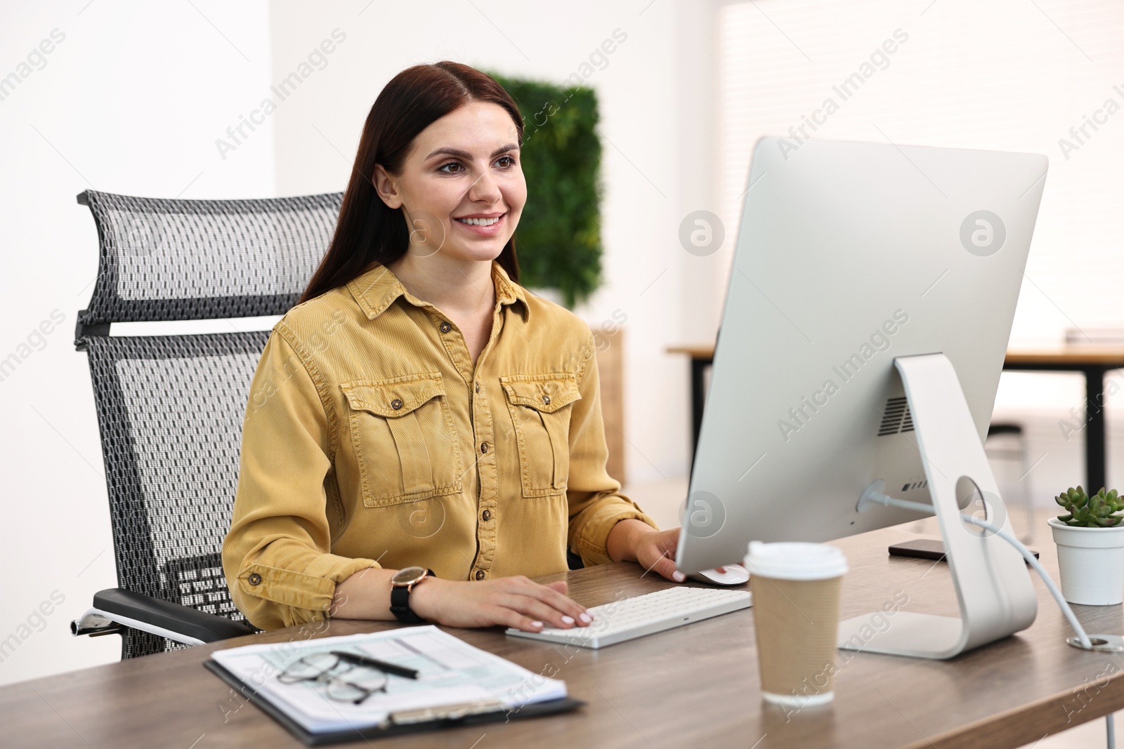 Photo of Woman working on computer at table in office