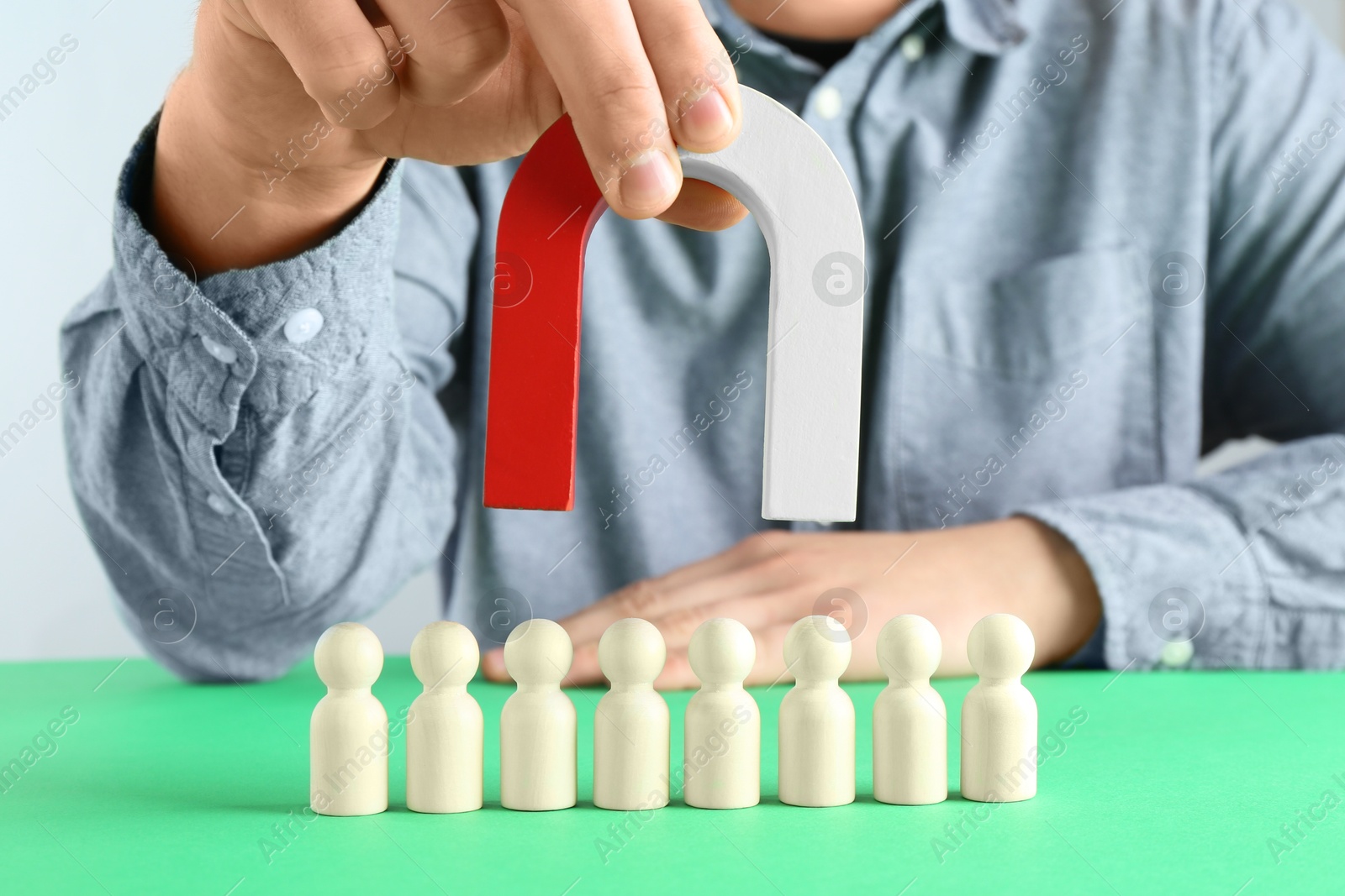 Photo of Man with magnet attracting game pieces at green table, closeup