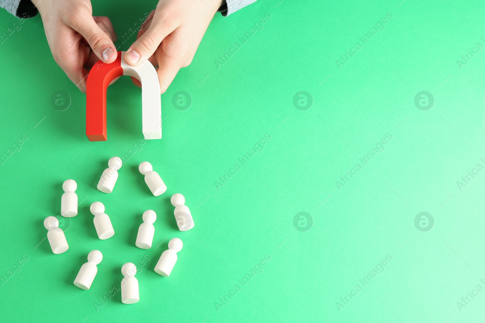 Photo of Man with magnet attracting game pieces at green table, above view. Space for text