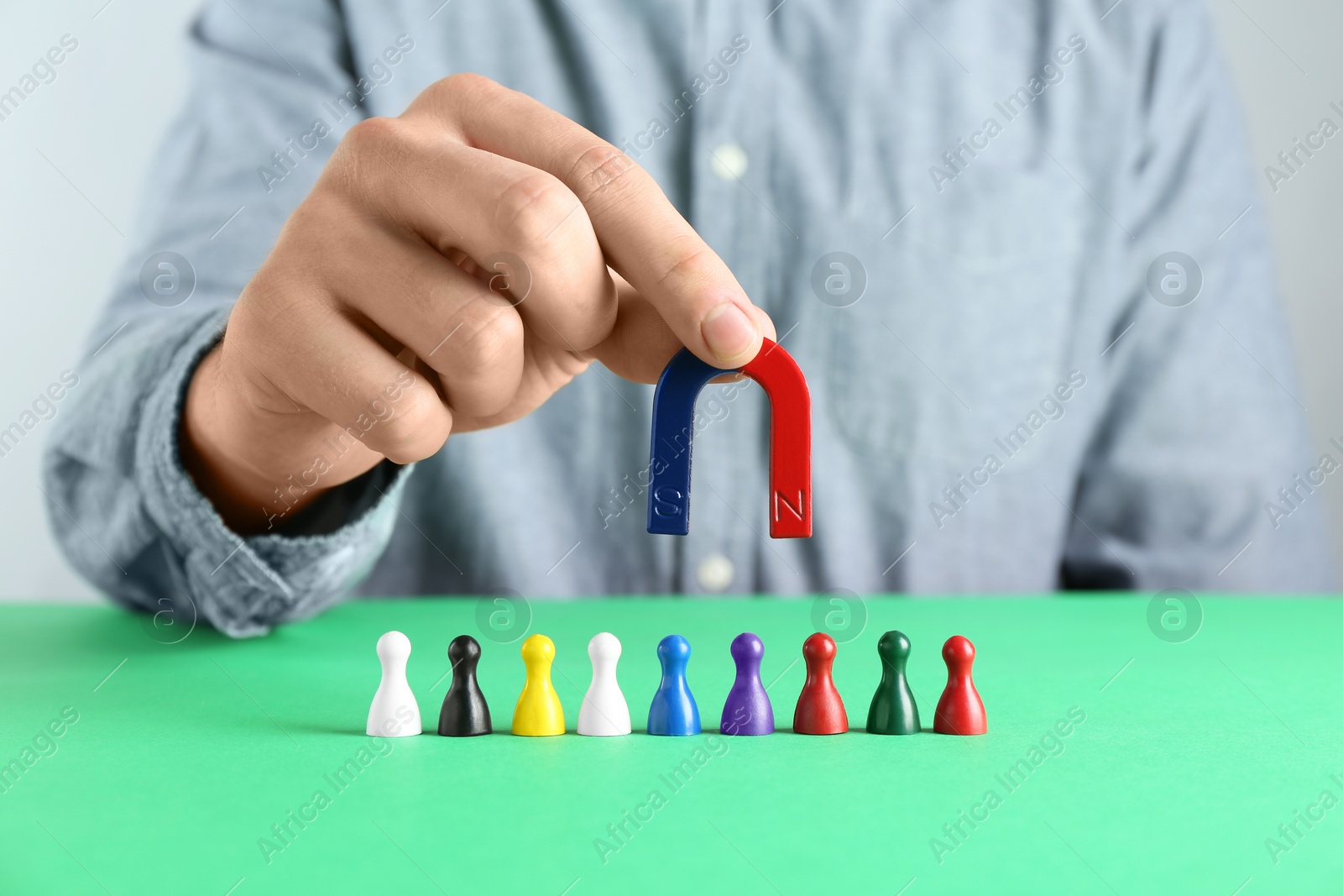 Photo of Man with magnet attracting game pieces at green table, closeup