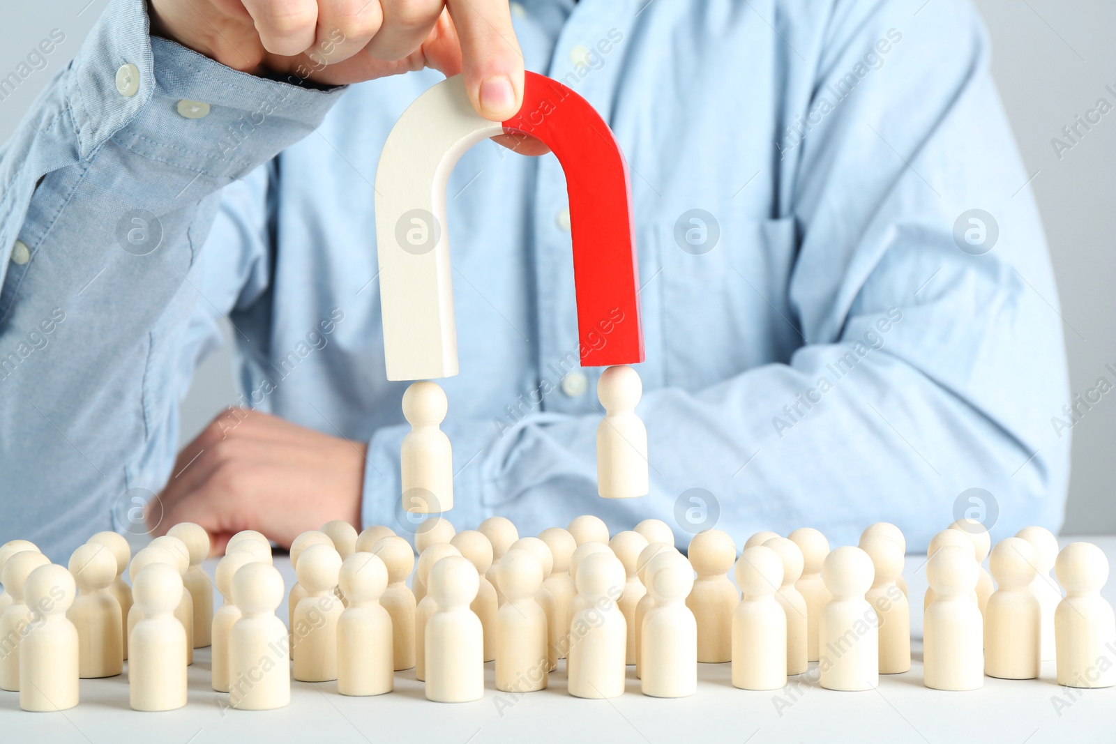 Photo of Man with magnet attracting game pieces at white table, closeup