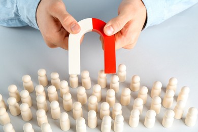 Photo of Man with magnet attracting game pieces at white table, closeup