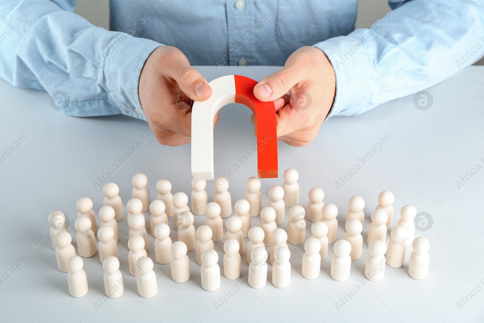 Photo of Man with magnet attracting game pieces at white table, closeup