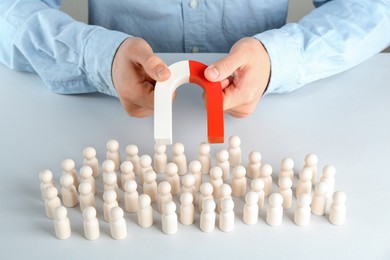 Photo of Man with magnet attracting game pieces at white table, closeup