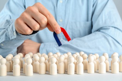 Photo of Man with magnet attracting game pieces at white table, closeup