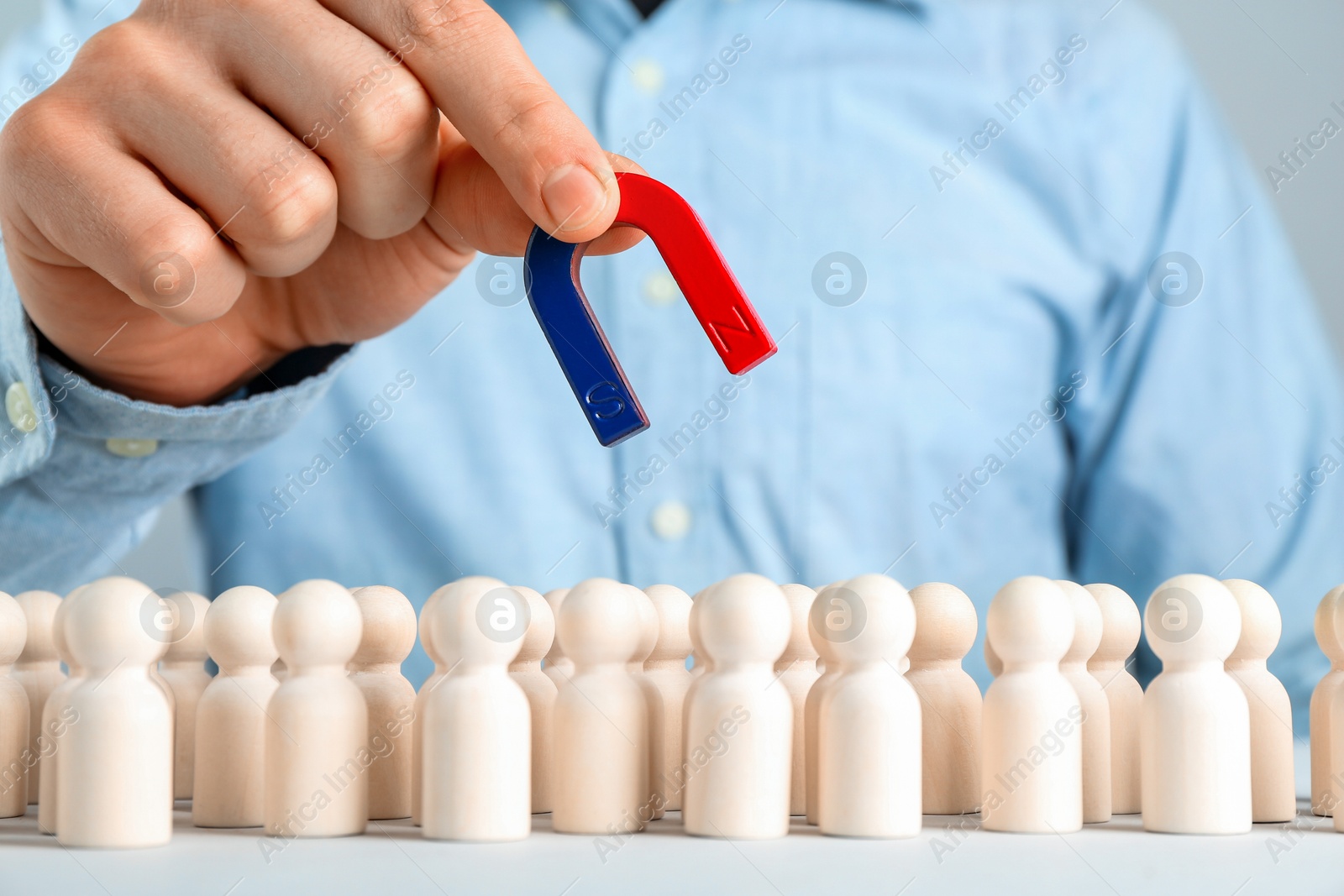 Photo of Man with magnet attracting game pieces at white table, closeup