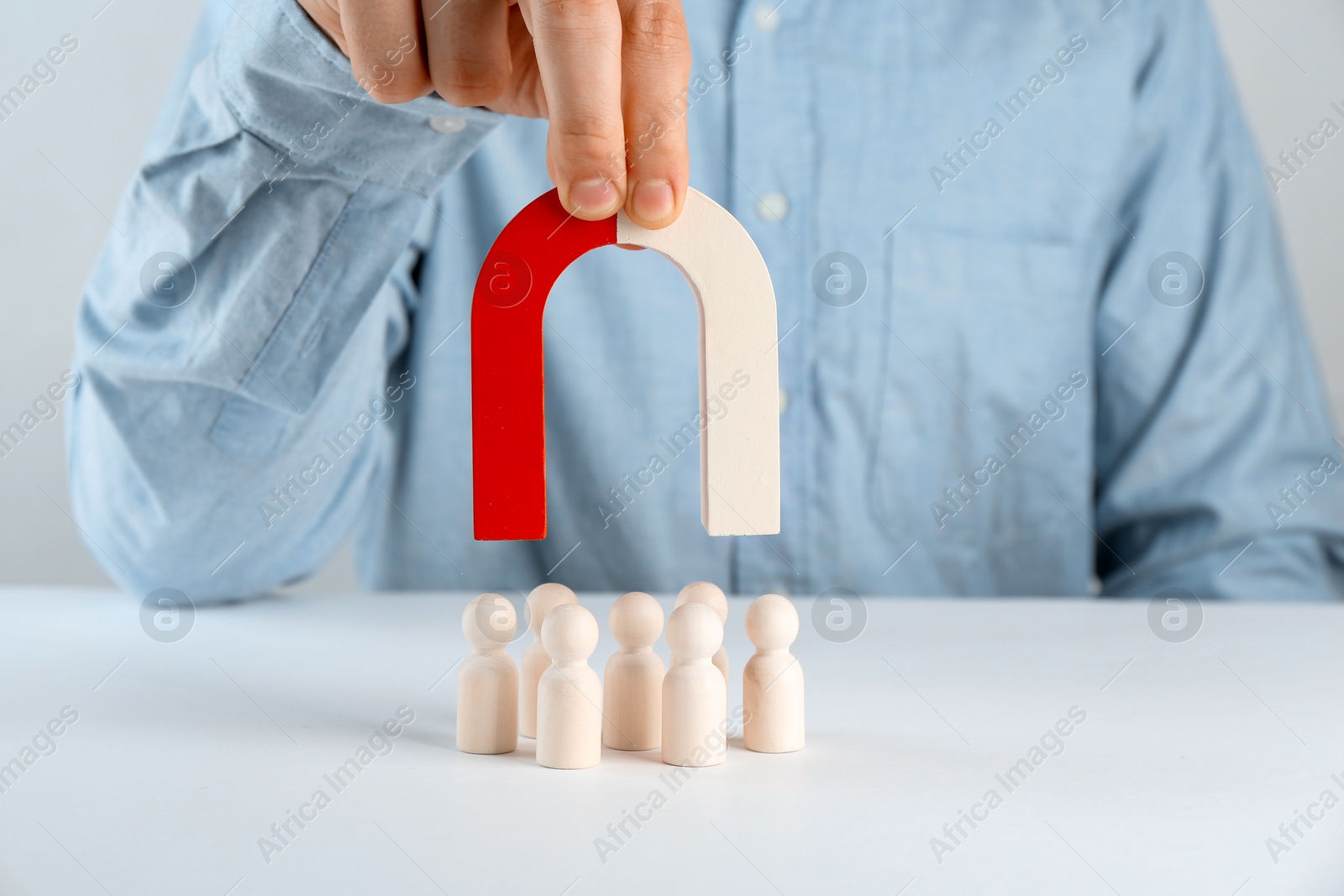 Photo of Man with magnet attracting game pieces at white table, closeup