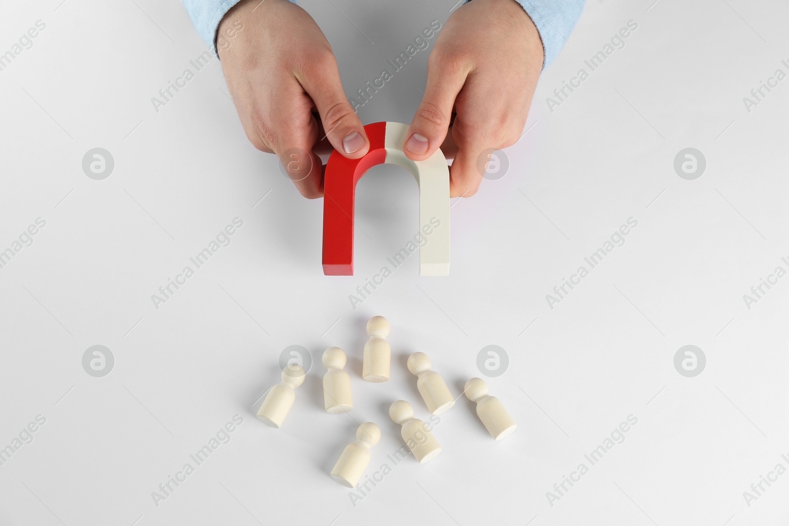 Photo of Man with magnet attracting game pieces at white table, above view