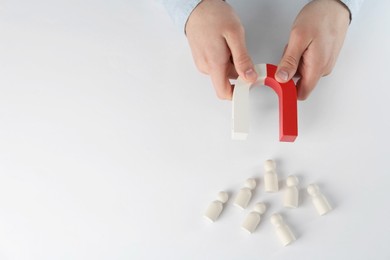 Photo of Man with magnet attracting game pieces at white table, above view. Space for text