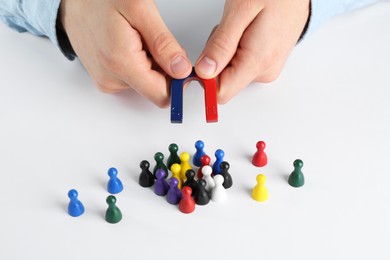 Photo of Man with magnet attracting game pieces at white table, closeup