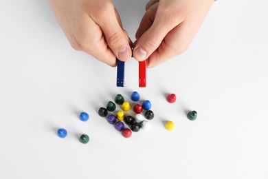 Photo of Man with magnet attracting game pieces at white table, above view