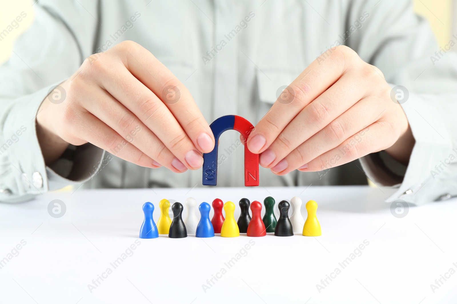 Photo of Woman with magnet attracting game pieces at white table, closeup