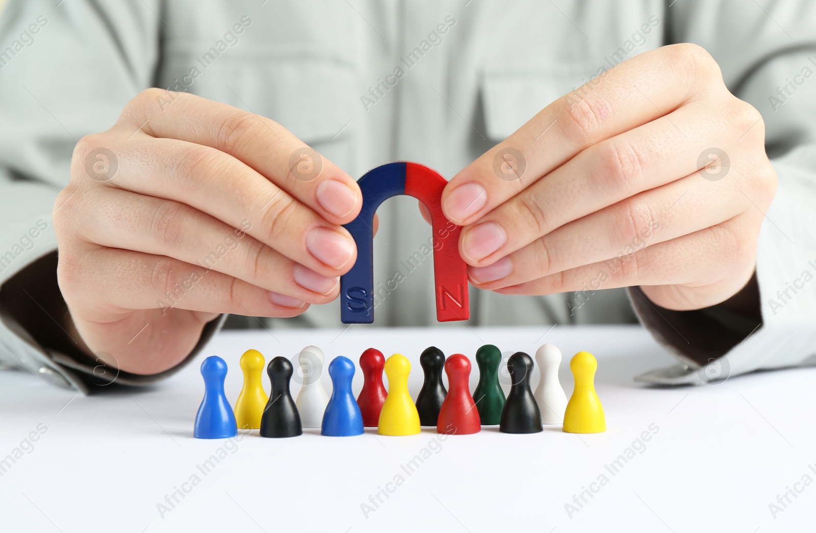 Photo of Woman with magnet attracting game pieces at white table, closeup