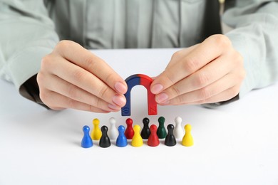 Photo of Woman with magnet attracting game pieces at white table, closeup