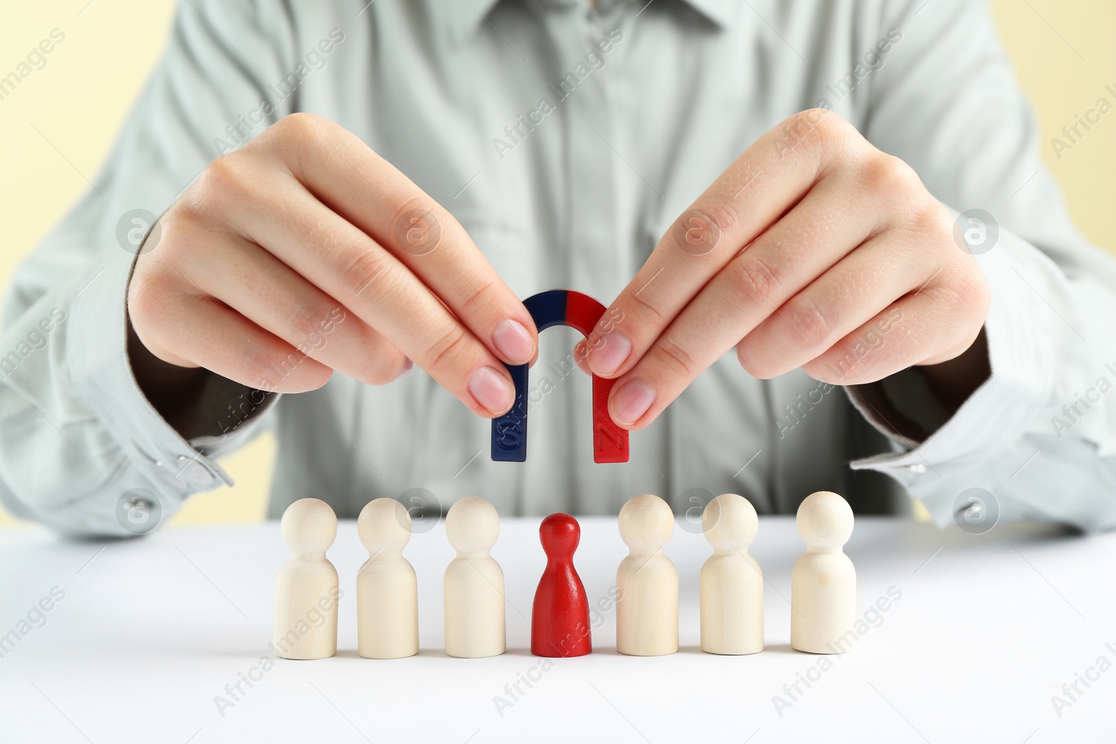 Photo of Woman with magnet attracting game pieces at white table, closeup