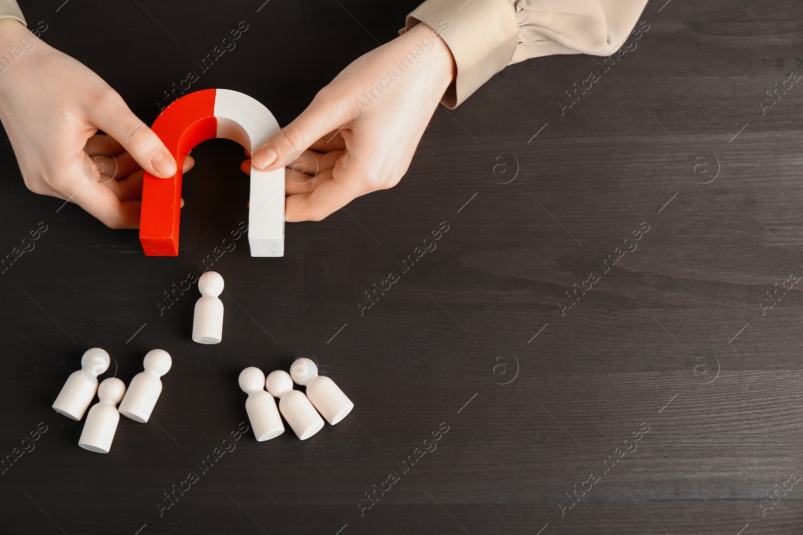 Photo of Woman with magnet attracting game pieces at wooden table, above view. Space for text