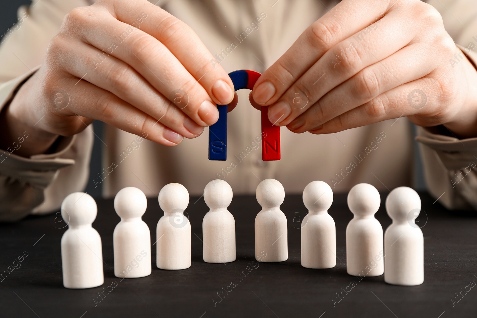 Photo of Woman with magnet attracting game pieces at wooden table, closeup