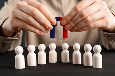 Photo of Woman with magnet attracting game pieces at wooden table, closeup